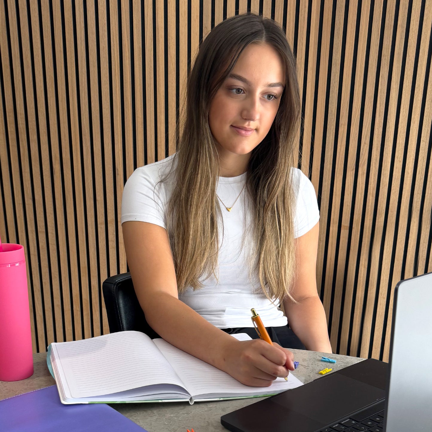 girl student writing with ballpoint pen at college with her stationery set
